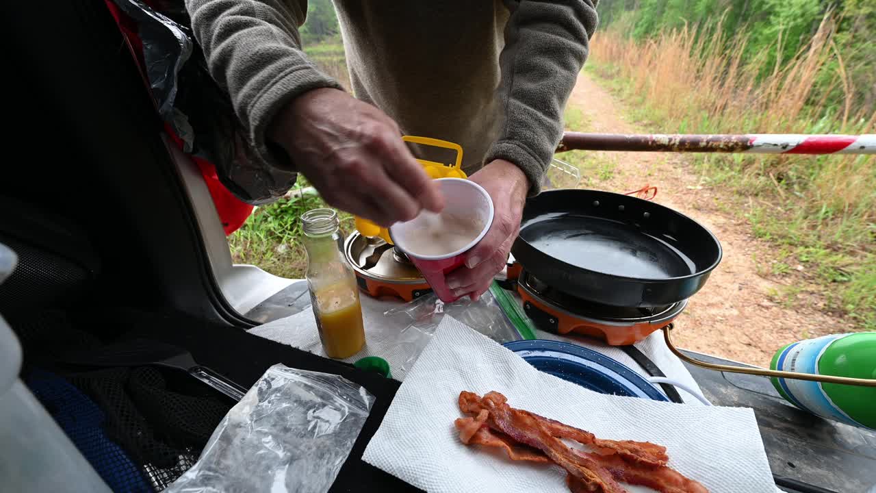 一名男子在陆地上的营地搅拌煎饼粉视频素材