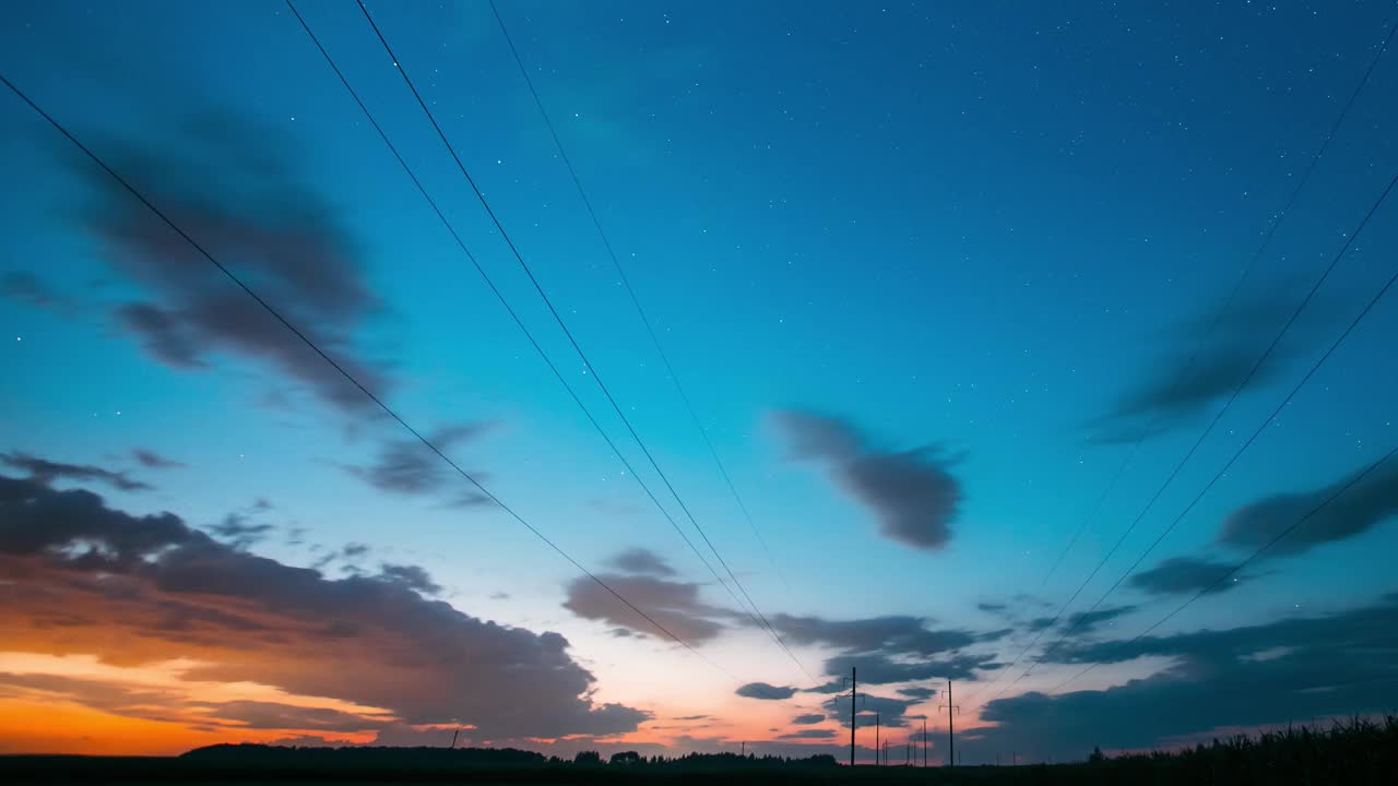 4K彩色日落天空过渡到黑夜星空与发光的星星和流星轨迹的踪迹。景观与电力线路在星空背景时移，时移，时移视频素材