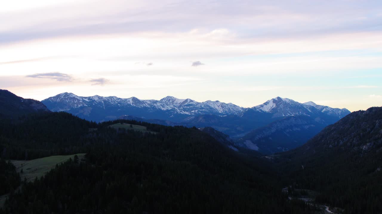 空中平移拍摄的森林附近的雪山对天空，无人机飞越自然景观在日落- Butte，蒙大拿州视频素材