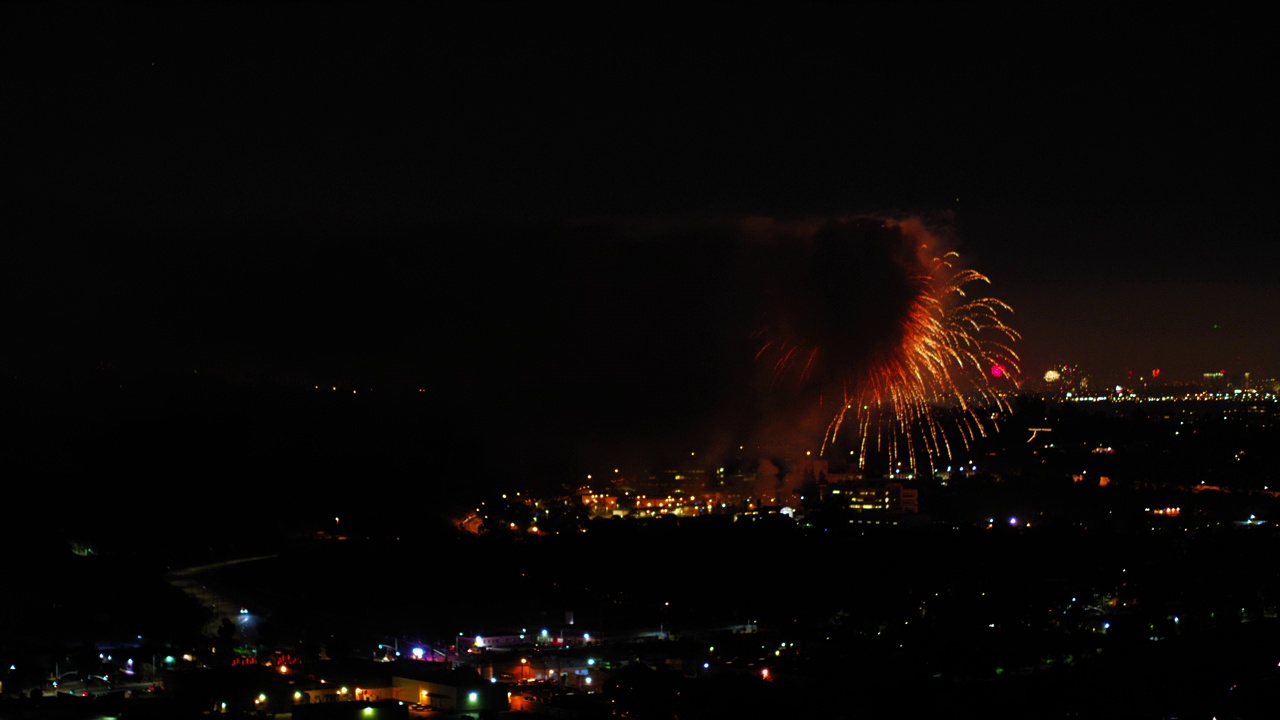 烟花在城市建筑物上爆炸的航拍照片，无人机在夜晚的城市景观上向后飞行，对着天空。洛杉矶，加利福尼亚视频素材