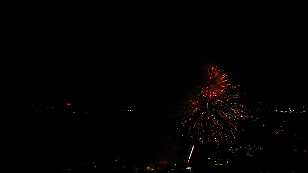 夜间，无人机在灯火通明的社区上空飞行，烟花在城市景观中爆炸的航拍照片-洛杉矶，加利福尼亚视频素材