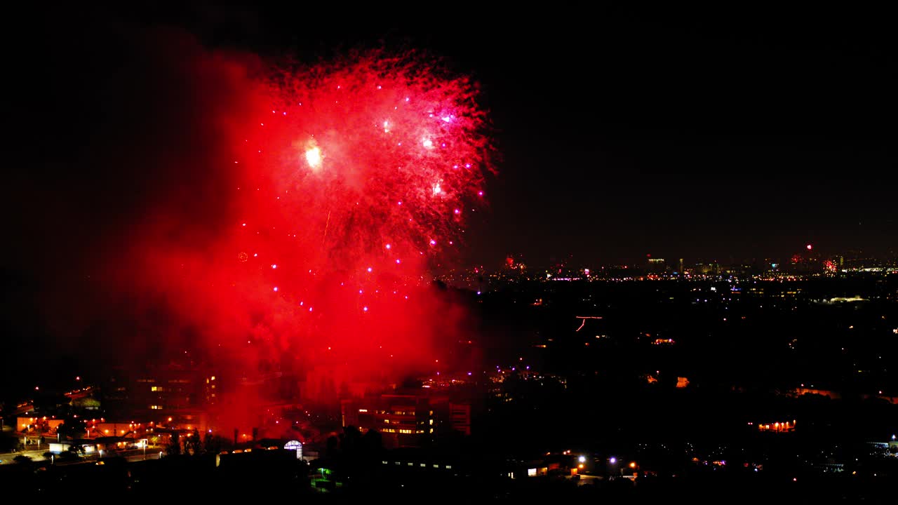 空中拍摄的烟花在附近对着天空爆炸，无人机在夜晚飞过城市景观-洛杉矶，加利福尼亚视频素材