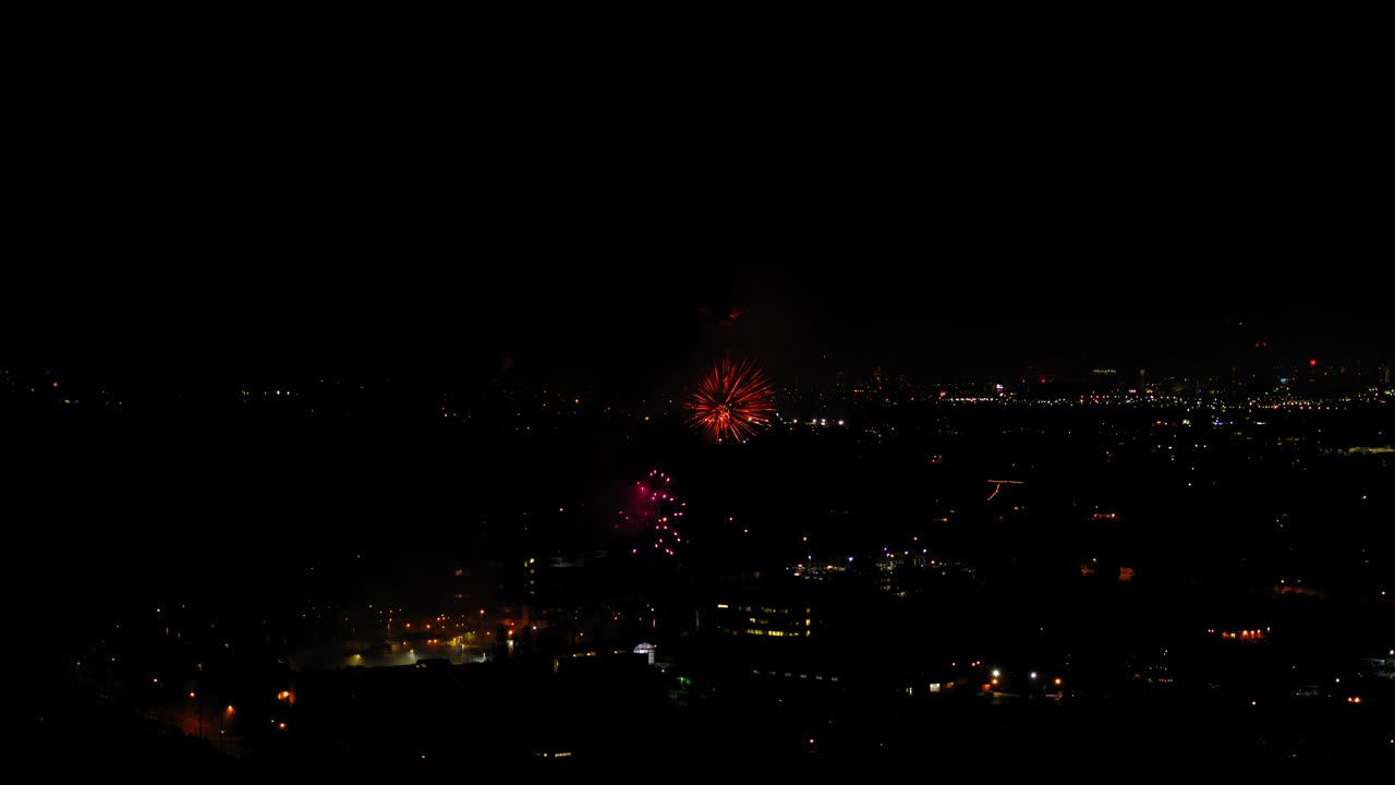 空中拍摄的烟花在城市附近爆炸，无人机在夜晚飞过灯火通明的城市景观-洛杉矶，加利福尼亚视频素材