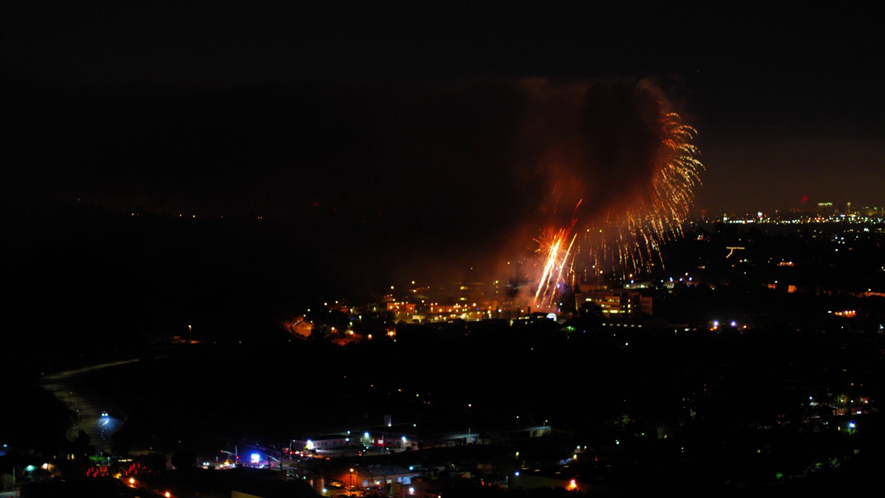 烟花在城市附近爆炸的航拍照片，无人机在夜晚的城市景观上逆空飞行-洛杉矶，加利福尼亚视频素材