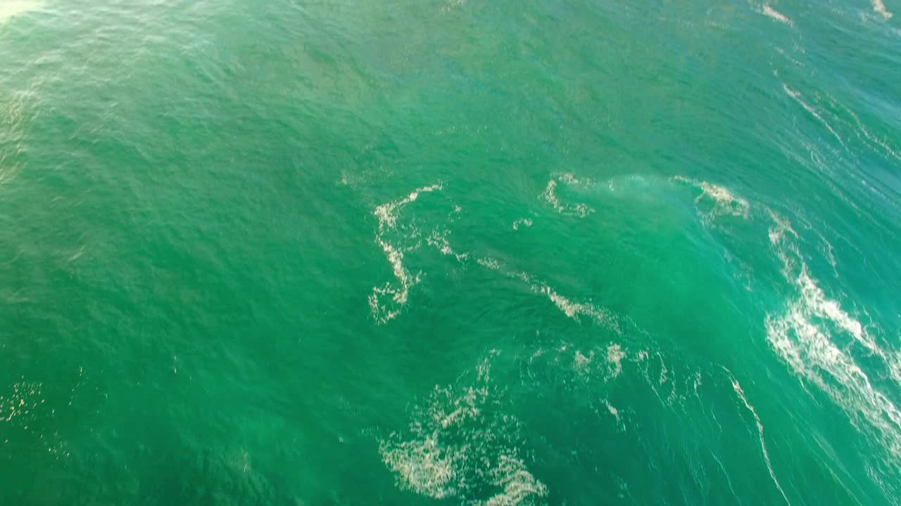 空中倾斜拍摄的人们在海浪上冲浪对着天空，无人机在海上飞行-瓦胡岛，夏威夷视频素材