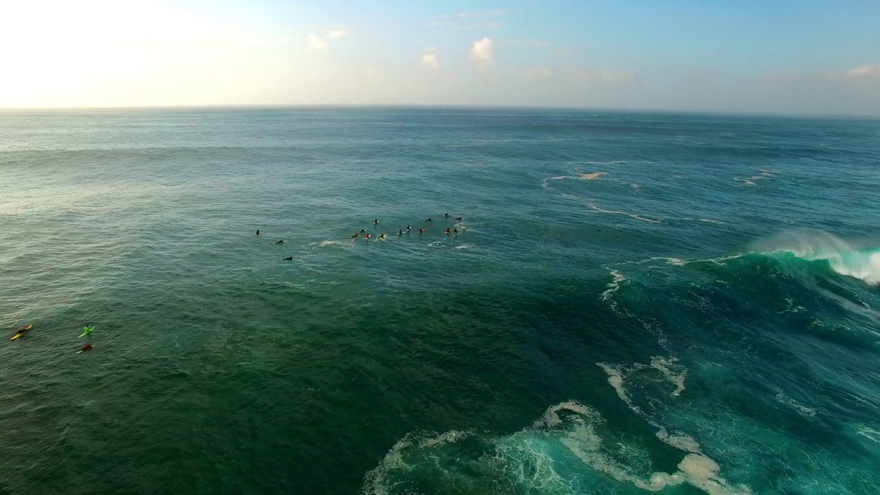 航拍拍摄的海浪溅在海岸线上对着天空，无人机飞过冲浪的人-瓦胡岛，夏威夷视频素材