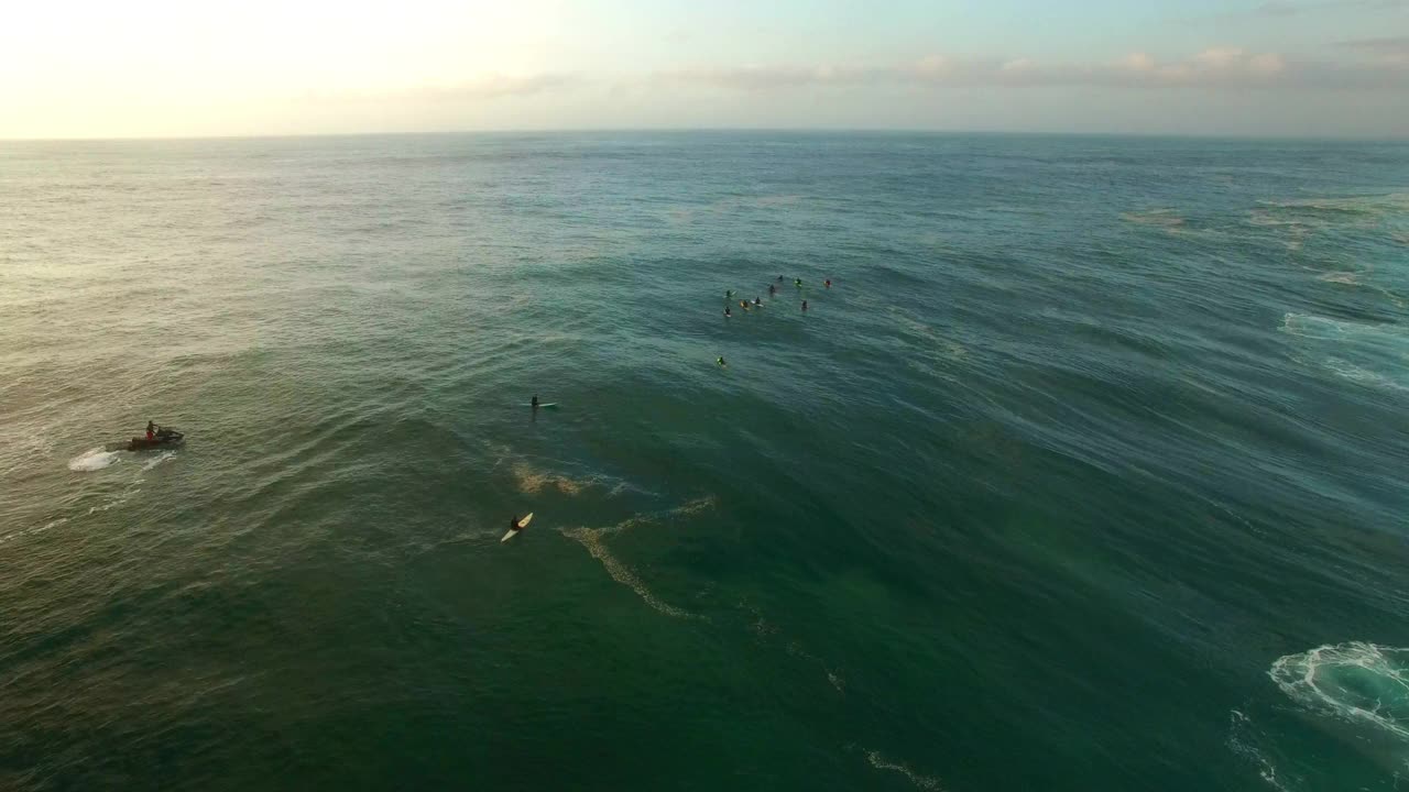 人们在海浪上冲浪的空中封锁镜头，无人机在日落时飞过冲浪者-夏威夷瓦胡岛视频素材