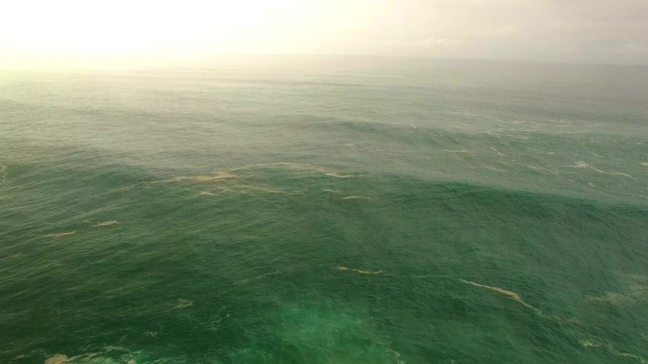 日落时，无人机在水上飞行，从空中倾斜拍下海面上的浪花与天空的对比——夏威夷瓦胡岛视频素材