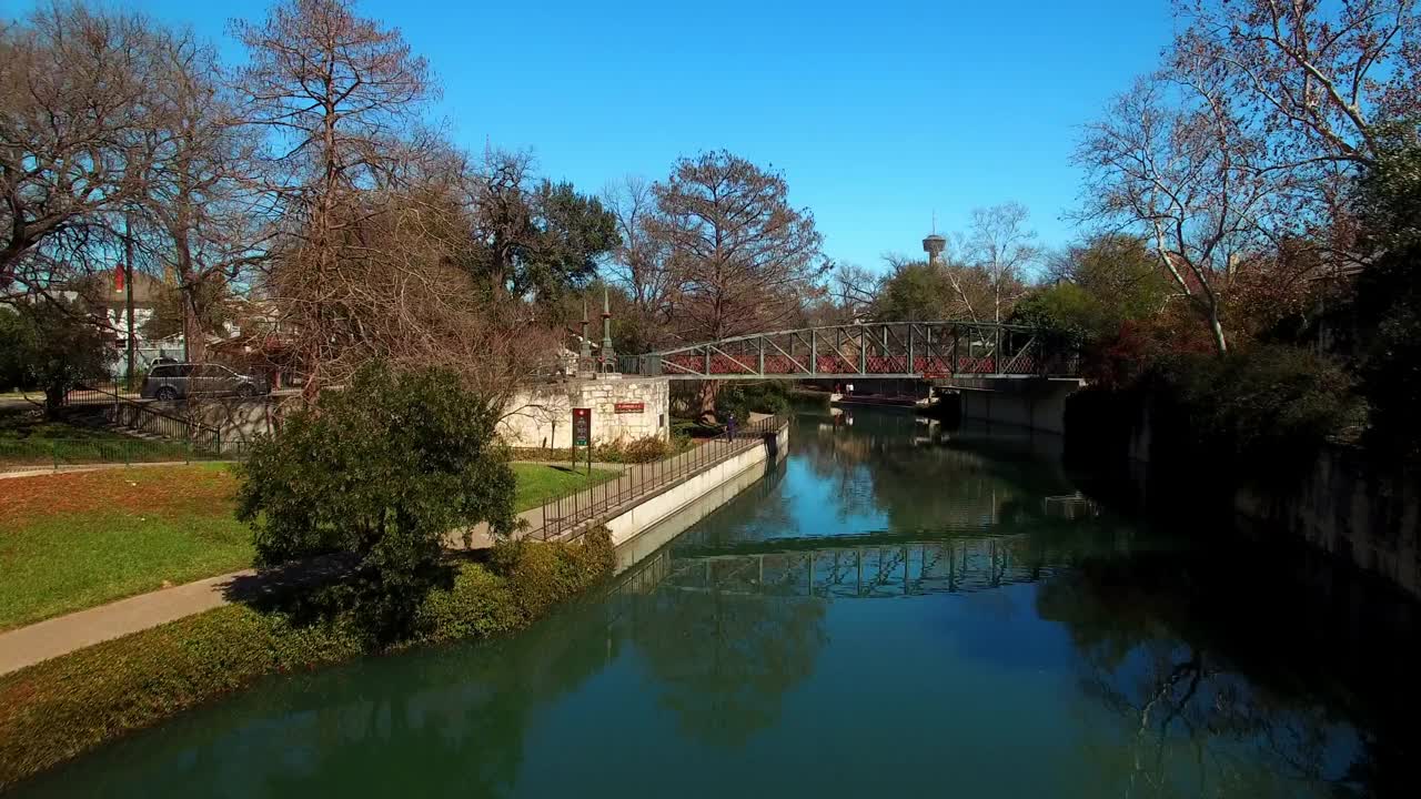 在阳光明媚的日子里，无人机在德克萨斯州圣安东尼奥市上空飞行，拍摄了郊区房屋在树林中的河流视频素材