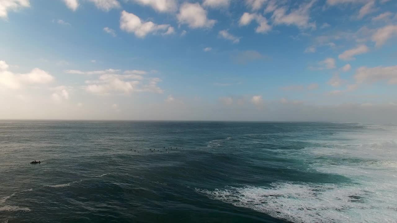 航拍的海浪附近的冲浪者在海上对着天空在日落，无人机向前飞行在泡沫-瓦胡岛，夏威夷视频素材