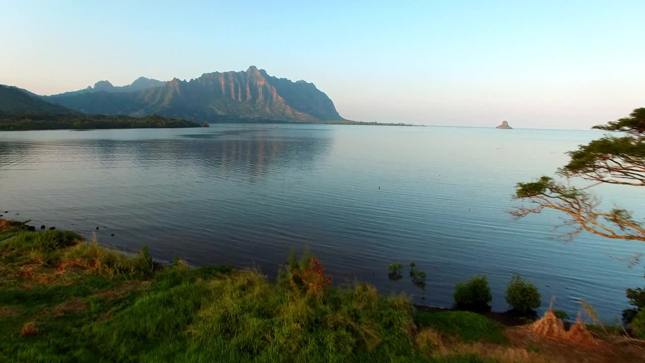 航拍的海洋附近的山脉对天空，无人机上升向前海岸线在日落-瓦胡岛，夏威夷视频素材