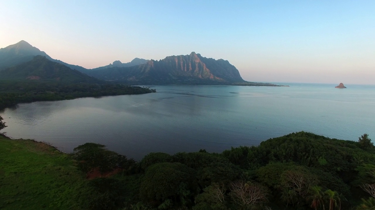 日落时，无人机在夏威夷瓦胡岛上空拍摄的海洋和山脉的空中平移镜头视频素材