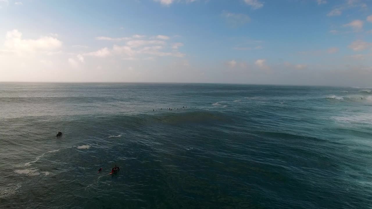 在日落时，无人机在海上飞行，人们在海浪上冲浪的空中封锁镜头-夏威夷瓦胡岛视频素材