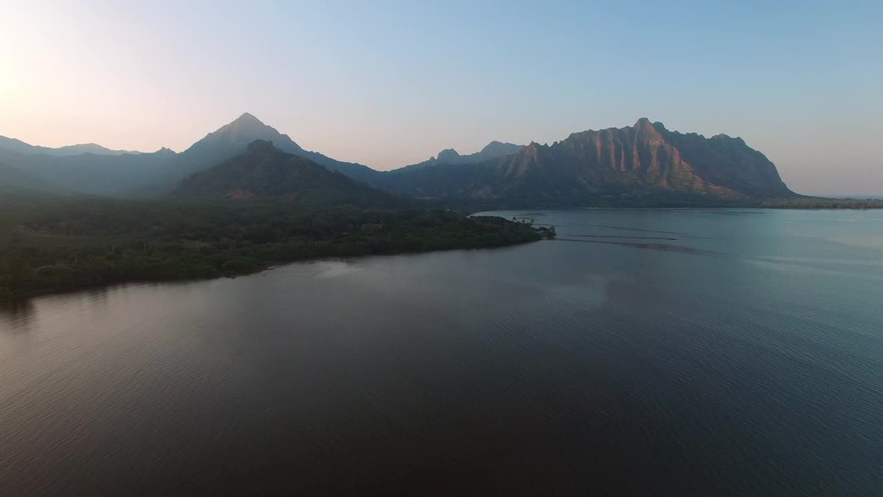 日落时，无人机在海岸线上向后飞行，航拍的海洋和山脉与天空的对比——夏威夷瓦胡岛视频素材