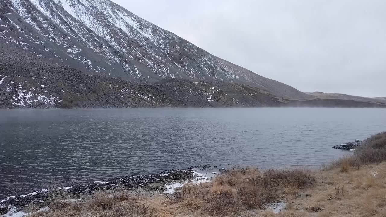 山脚下有一个美丽的湖边，覆盖着初秋的雪。视频素材