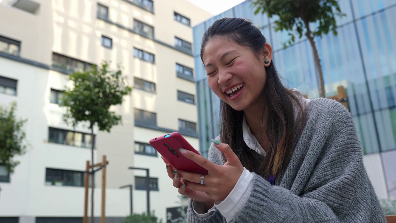 开心的女人一边笑一边看手机应用上有趣的社交媒体内容视频素材