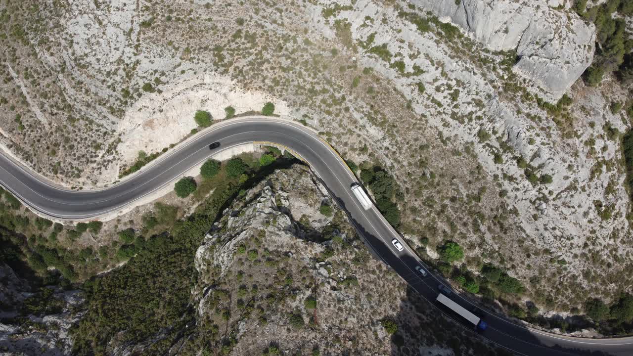 鸟瞰图，汽车和卡车行驶在弯曲的山路上。视频素材