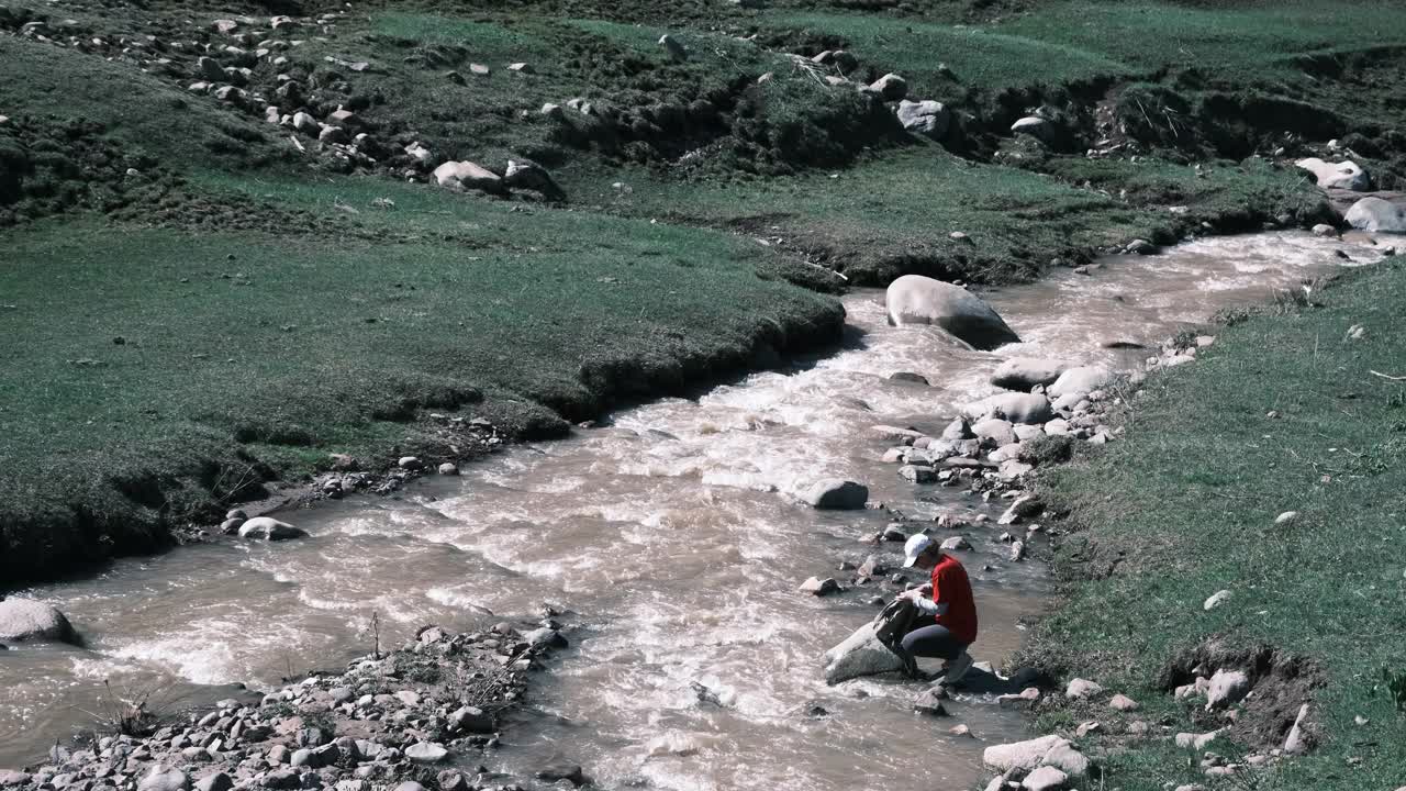 女徒步旅行者正在喝山河中的水视频素材