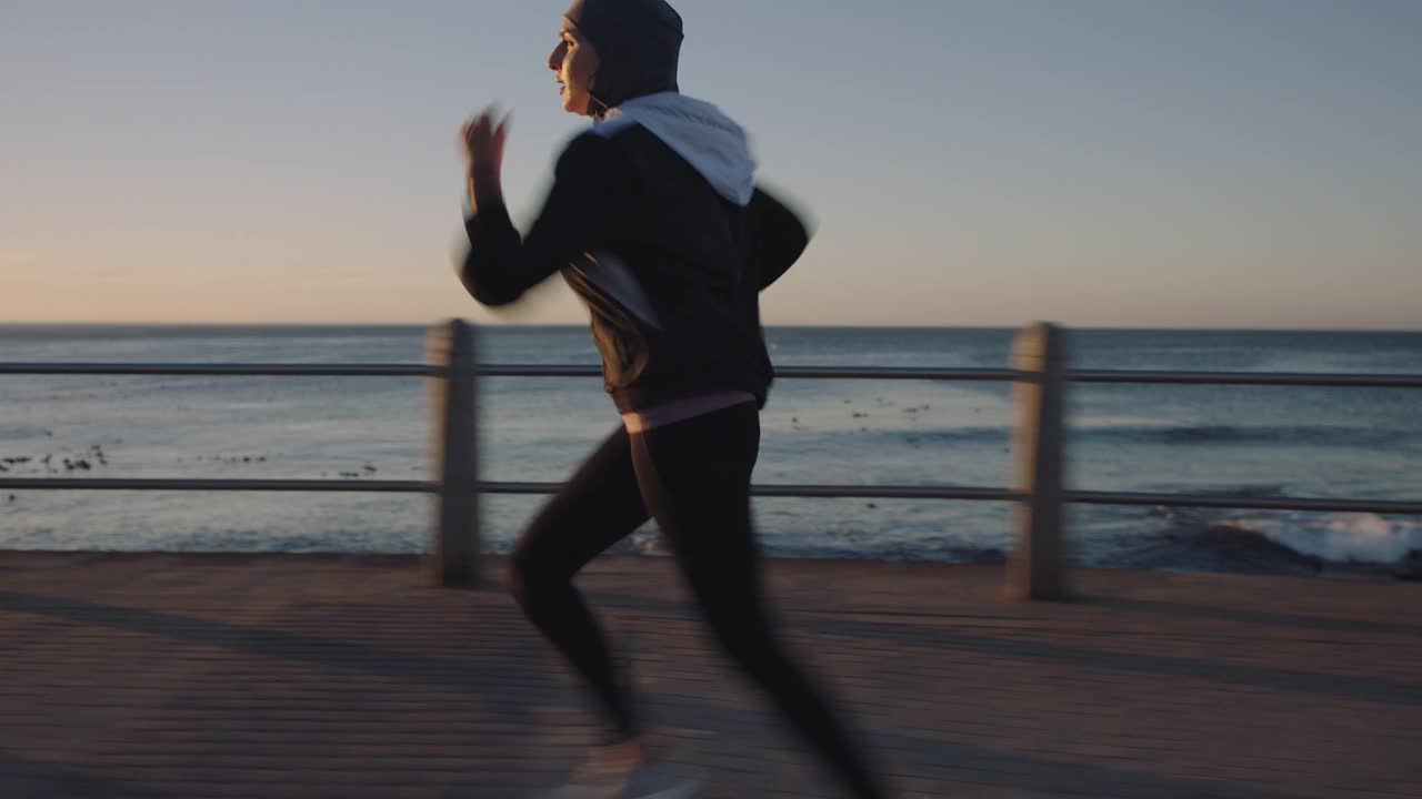 适合年轻的穆斯林妇女跑步锻炼慢跑耐力锻炼在海边日落独立的女性积极健身的生活方式视频素材