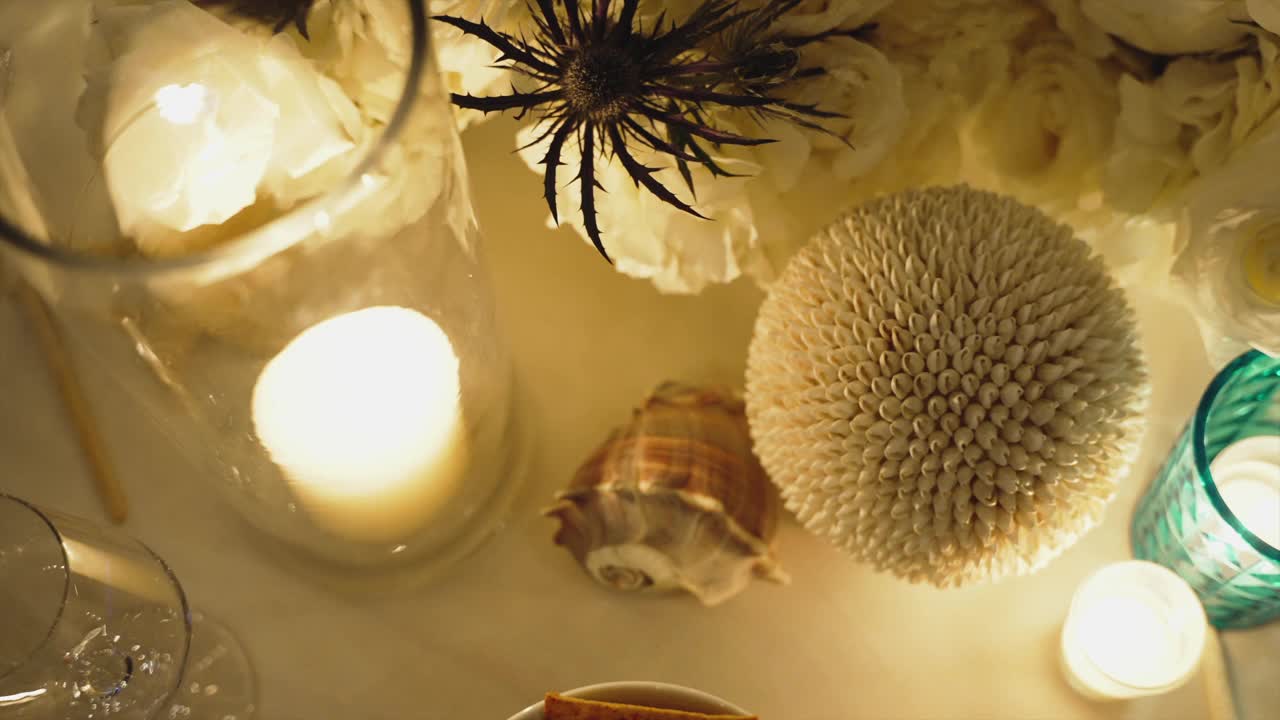 在黑暗中，由点燃的蜡烛、贝壳和鲜花组成的浪漫装饰的特写。视频素材