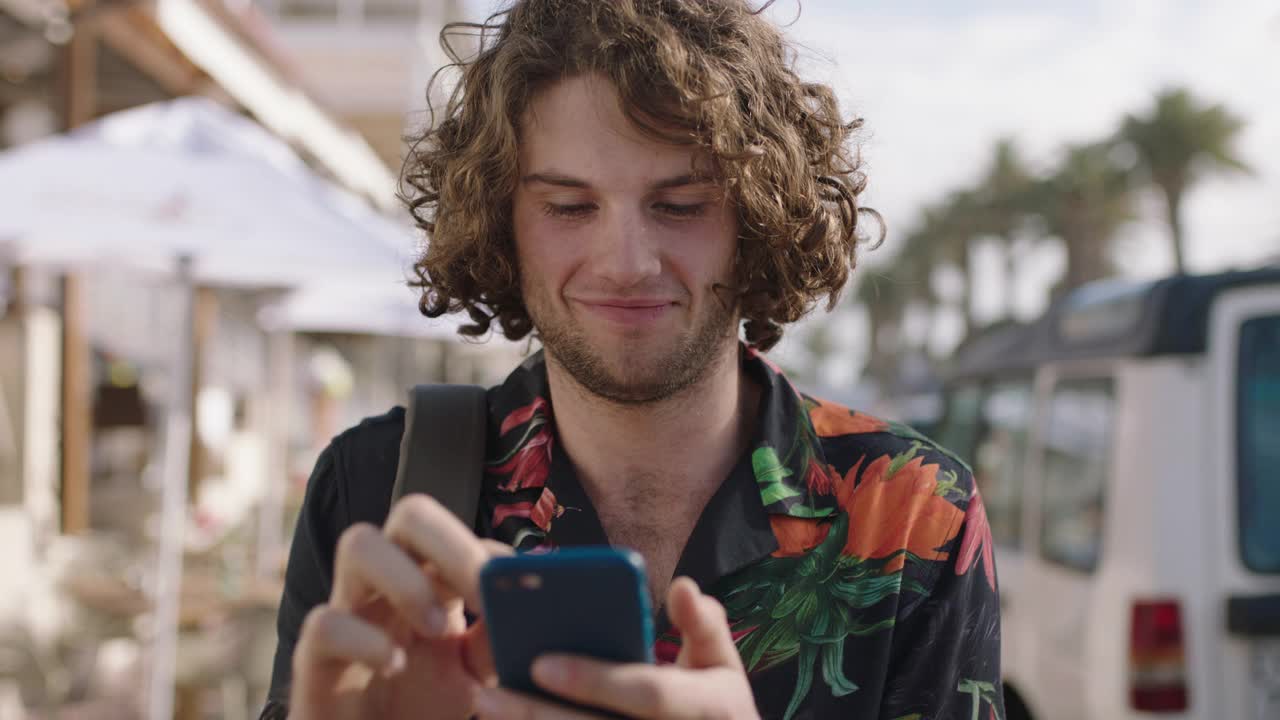 年轻迷人的男人穿着夏威夷衬衫用手机享受假期的肖像视频素材