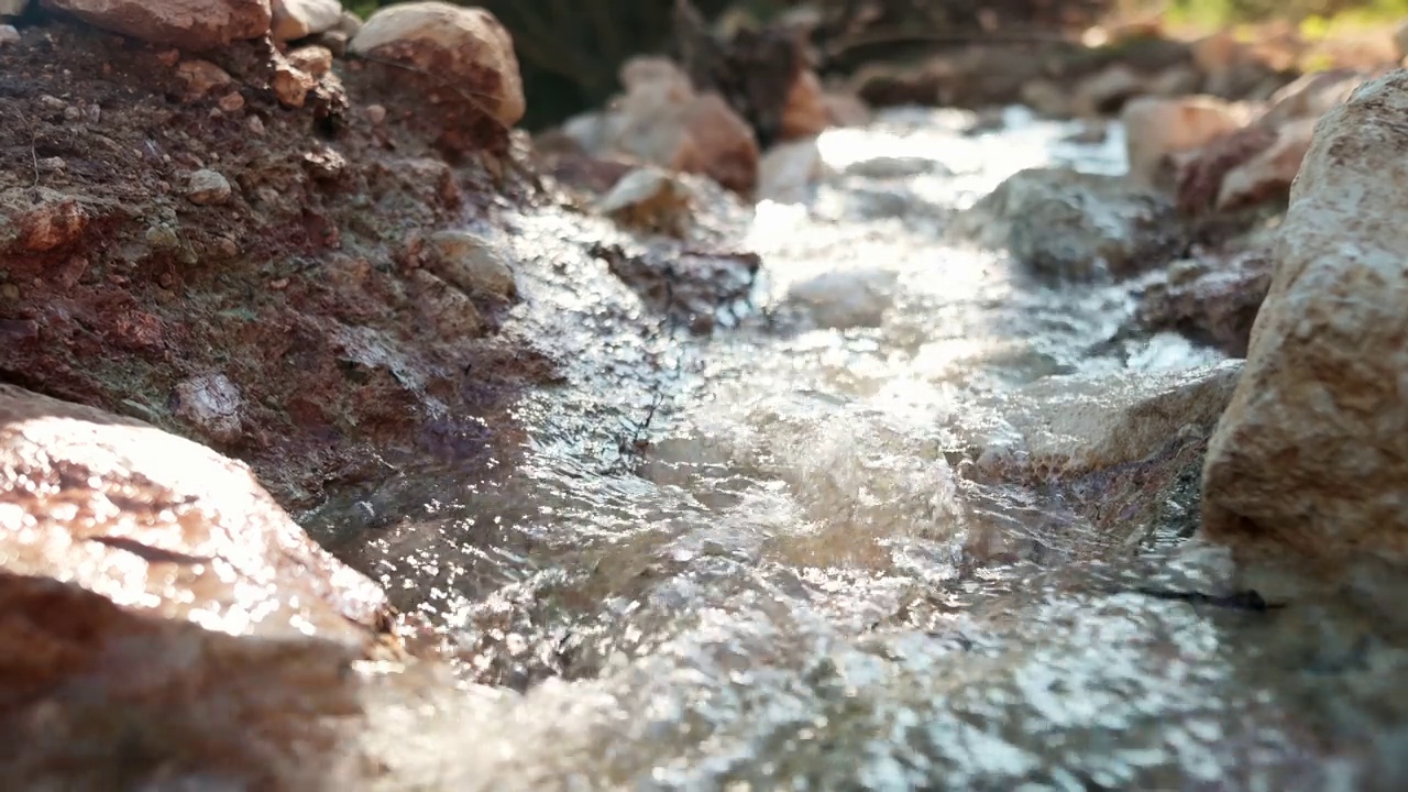 山间河流中最纯净透明的水在石头间流动的特写视频。山里阳光明媚的一天的细节。视频素材