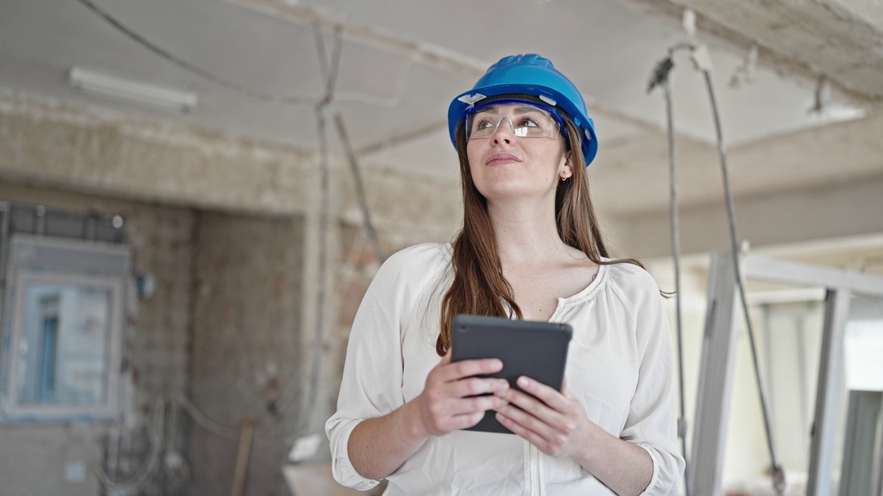 年轻漂亮的西班牙女建筑工人在工地上用触控板微笑视频素材