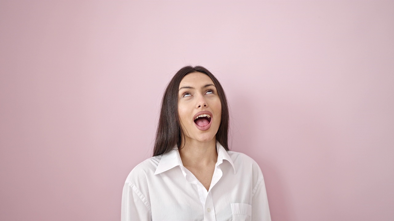 年轻漂亮的西班牙裔女子抬起头说“是”，她的头在孤立的粉色背景上视频素材