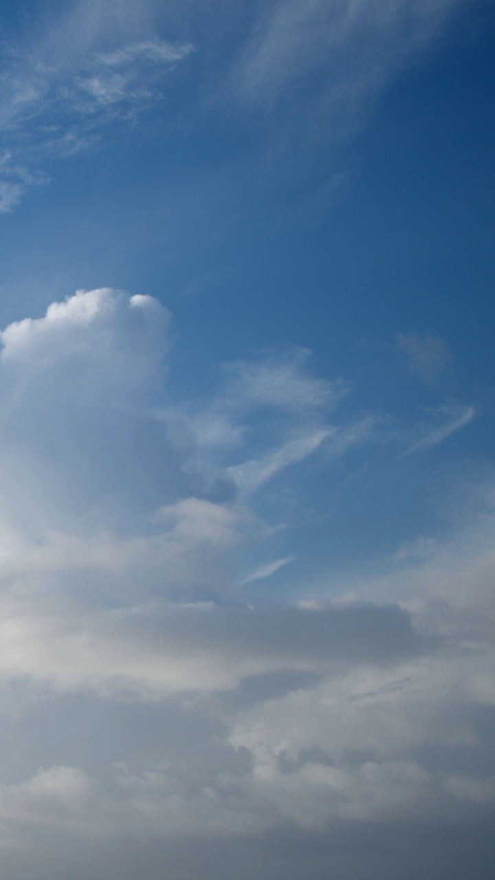 在炎热的天气里，当温暖潮湿的空气上升到很高的天空时，积雨云就会形成。从远处看，它们就像大山或高塔。多云的天空延时为背景。垂直视频。视频素材