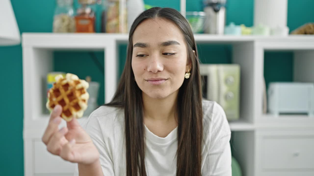 年轻漂亮的西班牙女人坐在餐桌上吃华夫饼视频素材