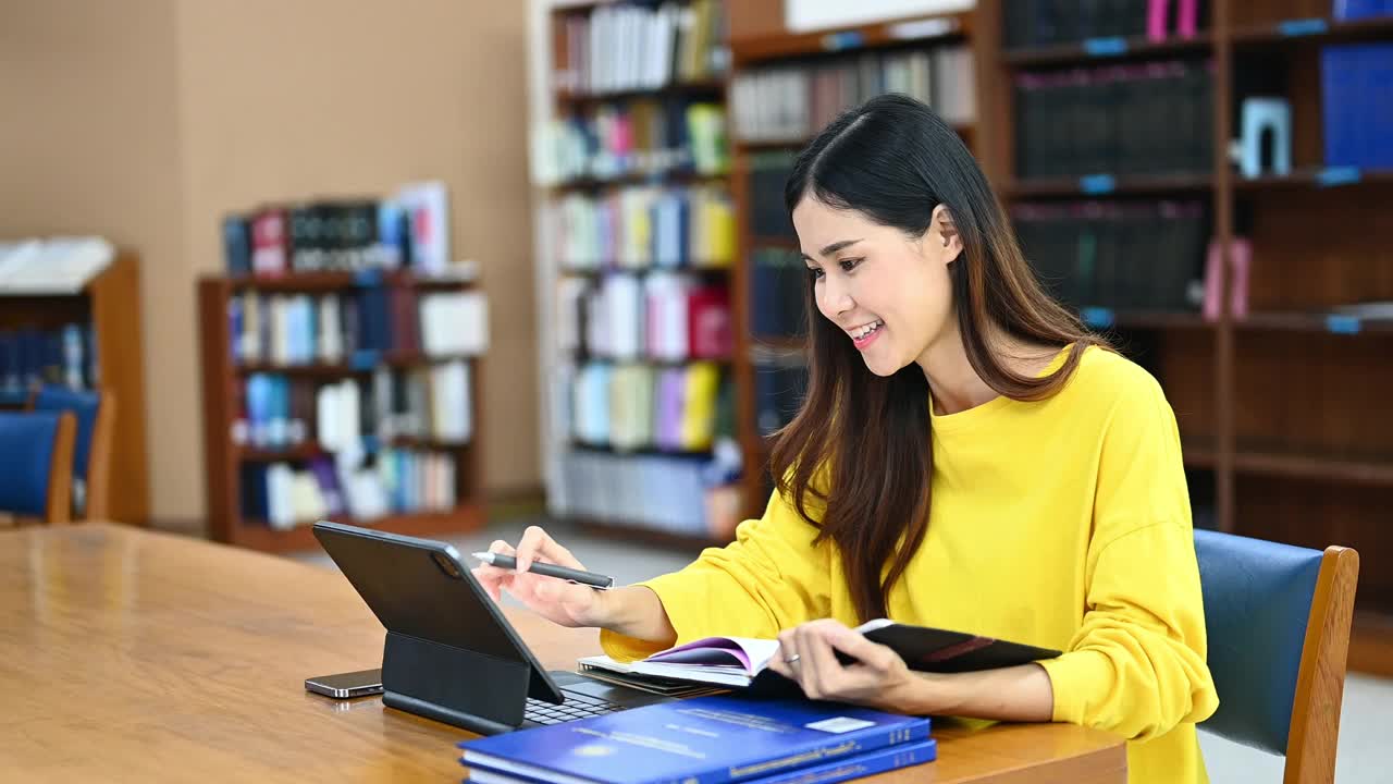 快乐的女学生使用数码平板电脑，查找数据信息和做笔记。教育，学习和技术。视频素材