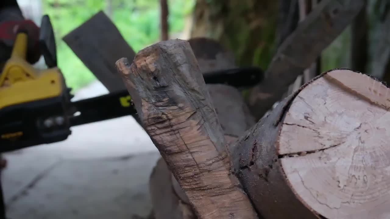 一位身穿工人制服的老人正在用电锯为冬天劈柴。视频素材