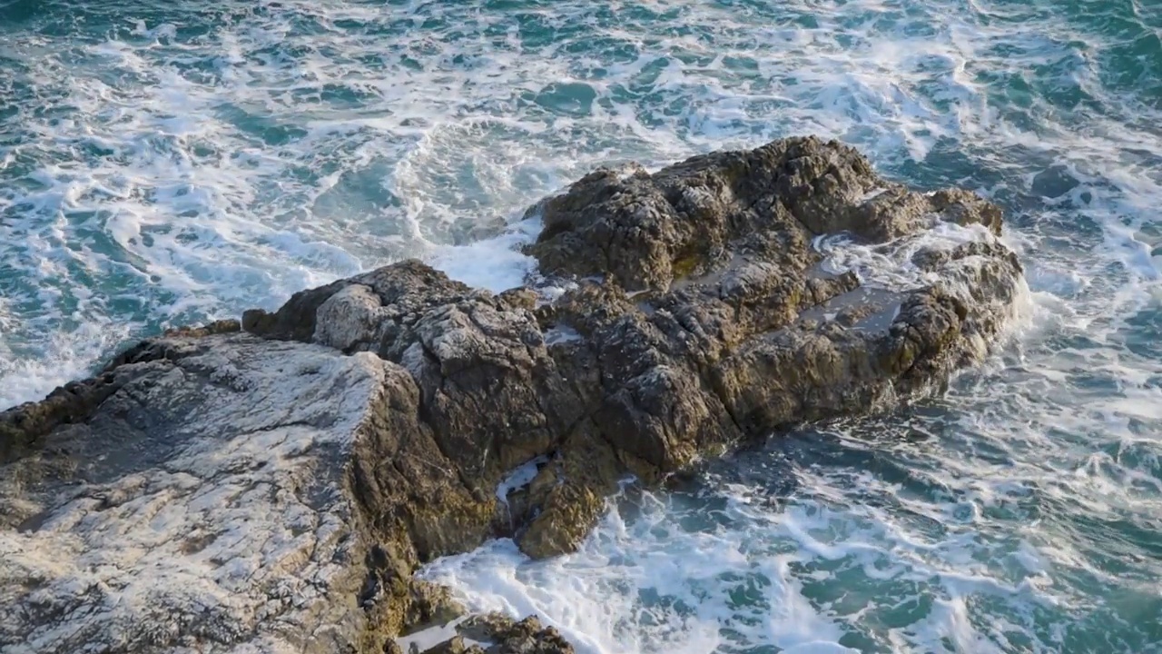 在夏天和阳光明媚的日子里，海浪冲击着岩石。视频素材