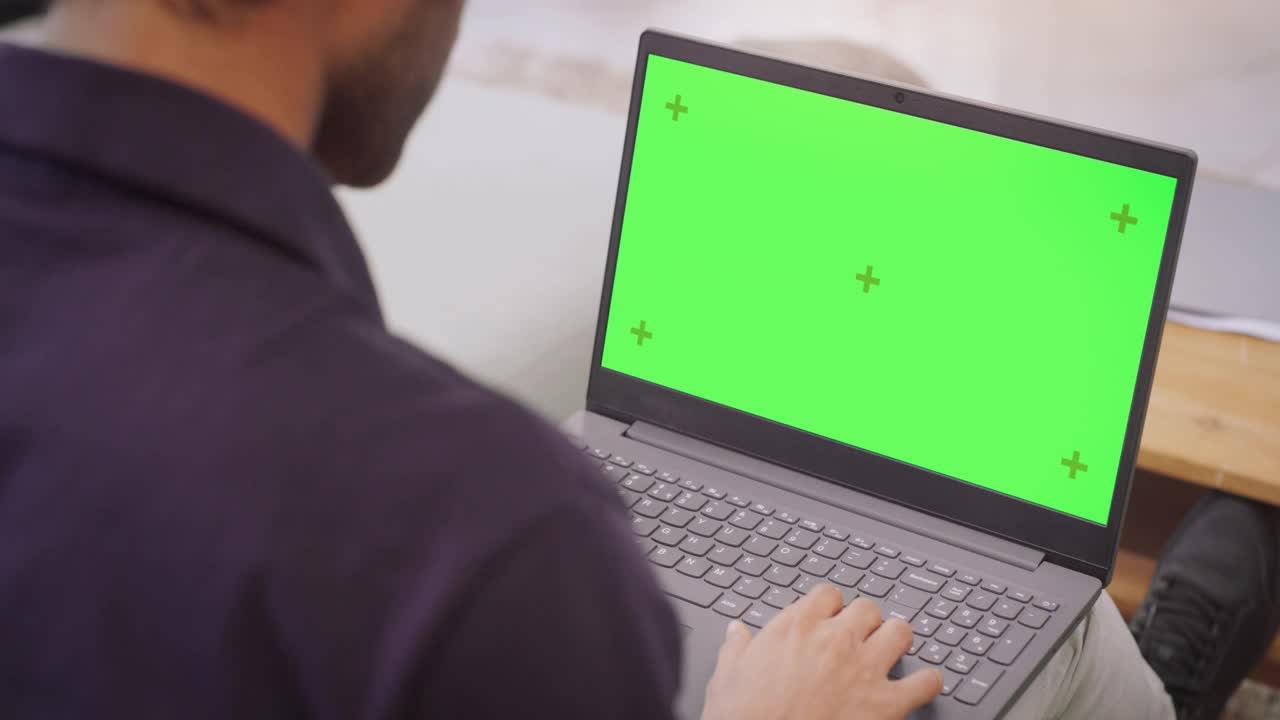 过肩:人使用笔记本电脑与绿色色度键屏幕:远程工作协作，视频会议。上网浏览，网上购物，使用创意软件。色度键视频素材