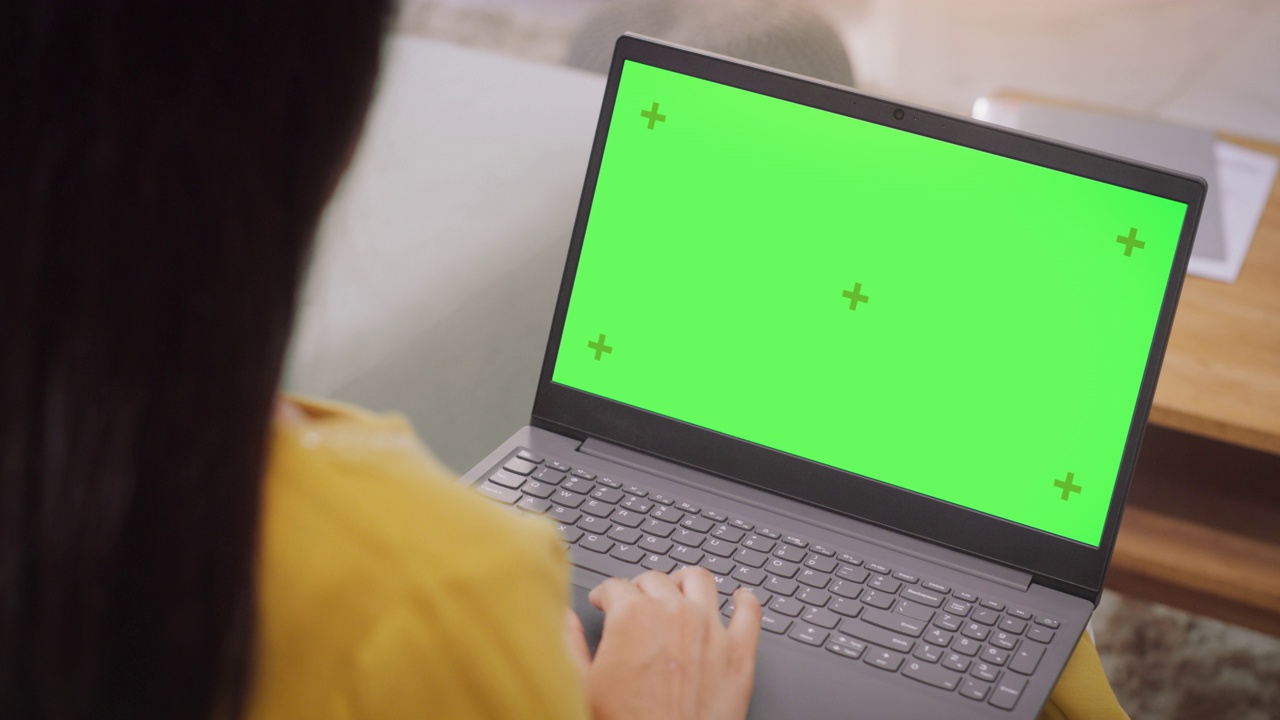 过肩:女性使用笔记本电脑与绿色色度键屏幕:远程工作协作，视频会议。上网浏览，网上购物，使用创意软件。色度键视频素材
