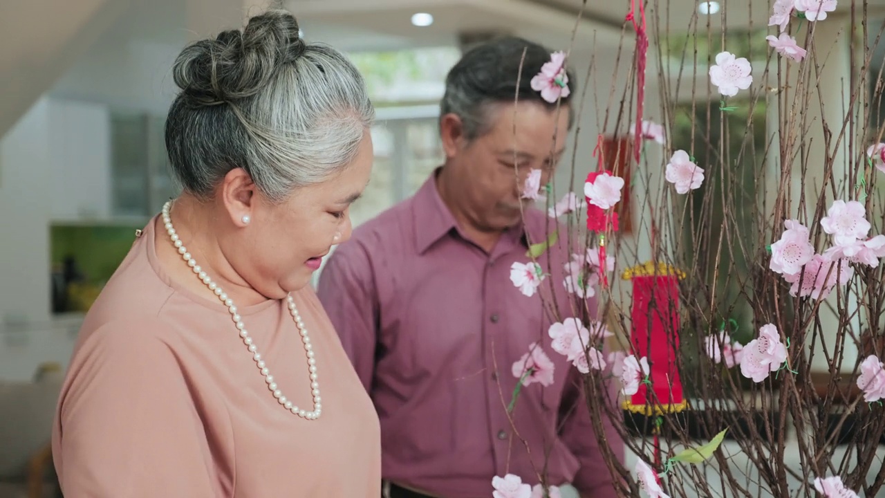 亚洲老夫妇在春节做桃花装饰视频素材