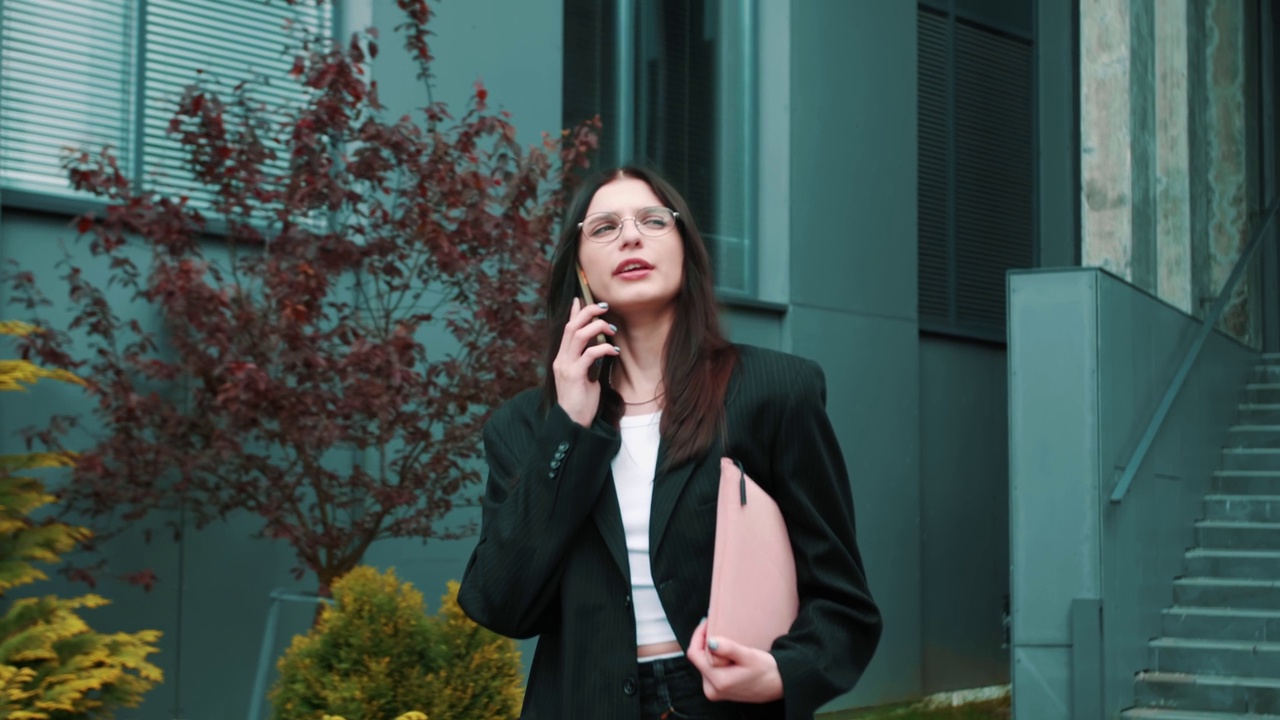 白人女商人女企业家走在城市的城市讲电话，交谈，接听电话，手里拿着笔记本电脑视频素材