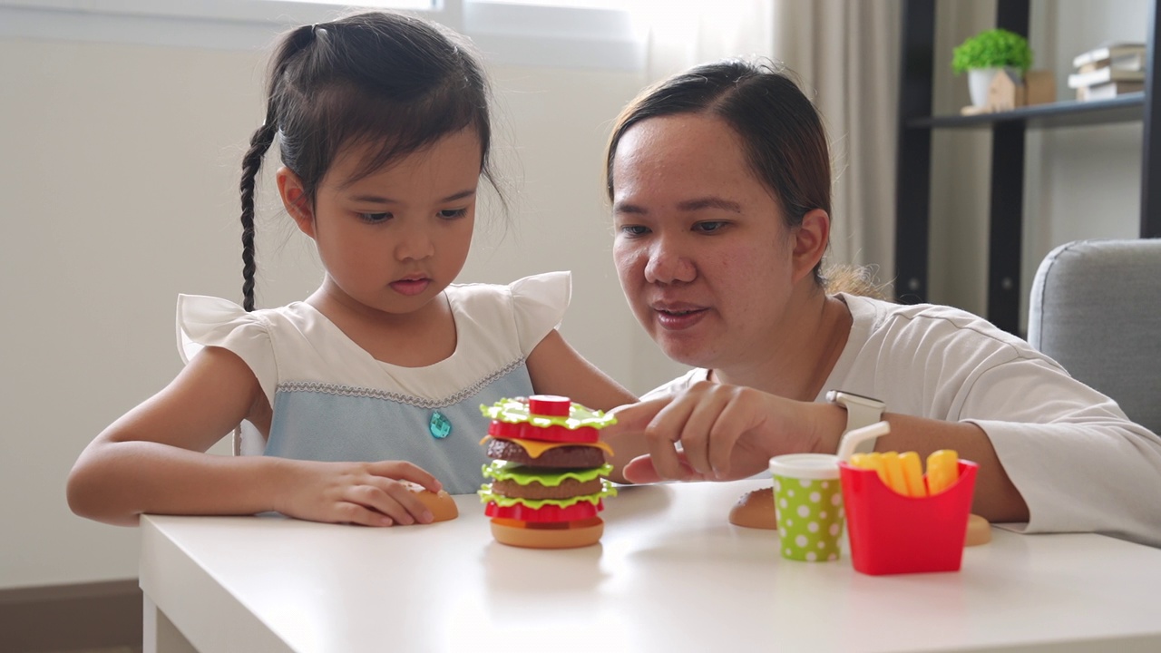 在想象中，妈妈和小女孩一起玩塑料儿童玩具视频素材