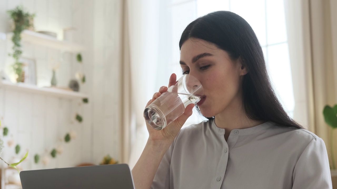 专注的白人女性工作和用水提神视频素材