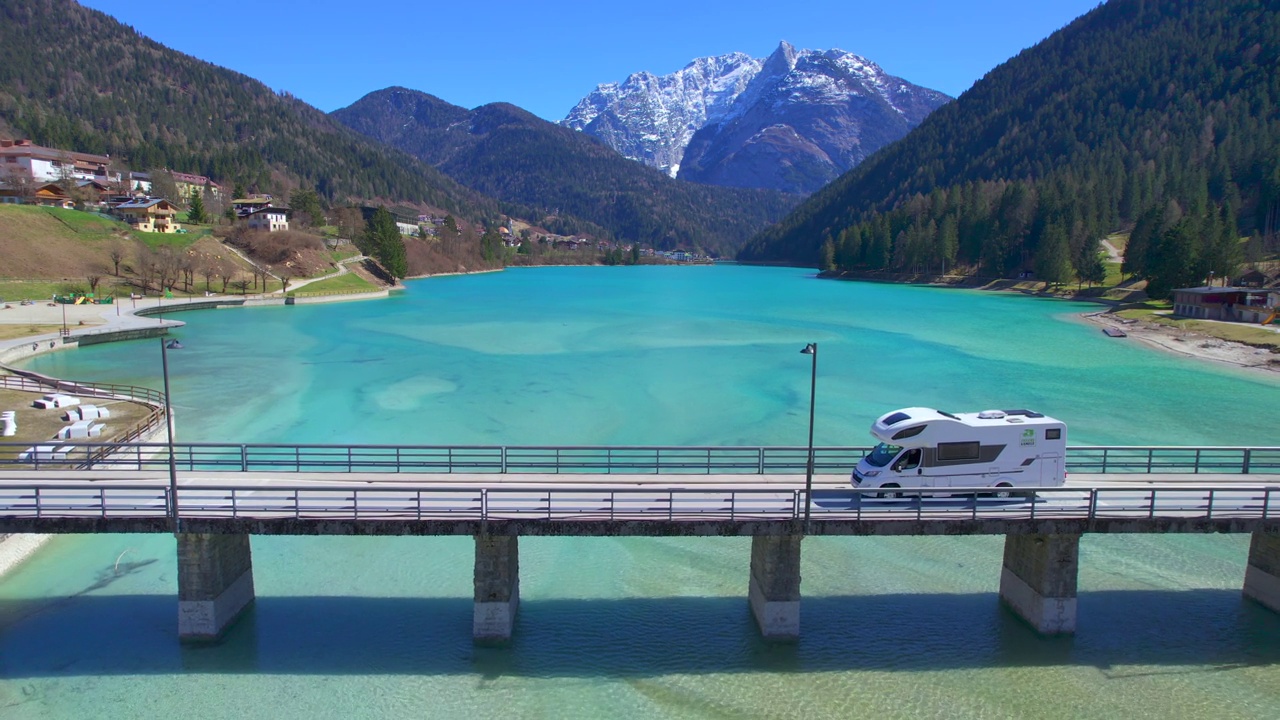 露营车(Campervan)通过湖上的桥梁。无人机视图(航拍照片)Auronzo di Cadore (Lago di Santa Caterina)是意大利文托省贝卢诺(Cadore)地区的人工湖。视频下载