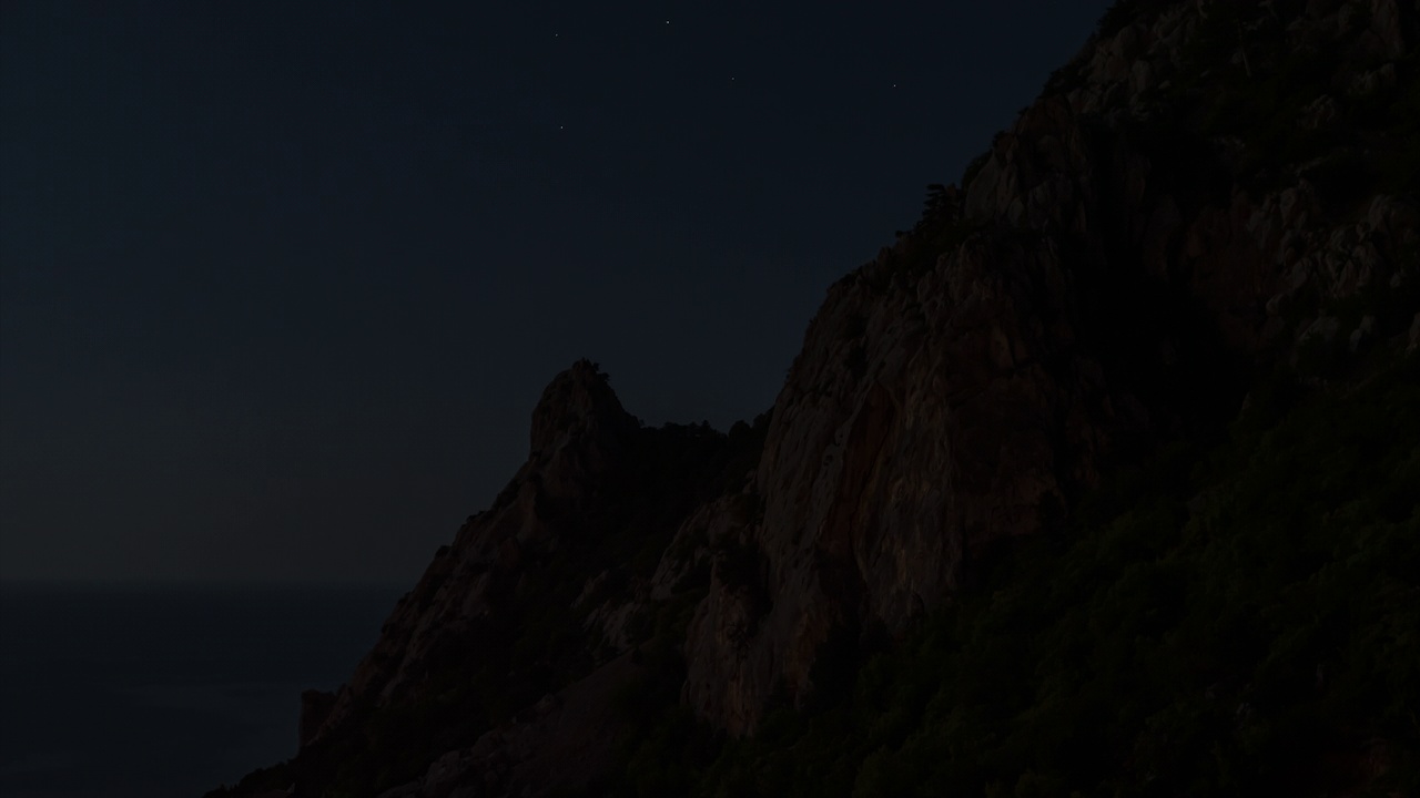 夜间拍摄。月光下的大海背景上的岩石山剪影视频下载