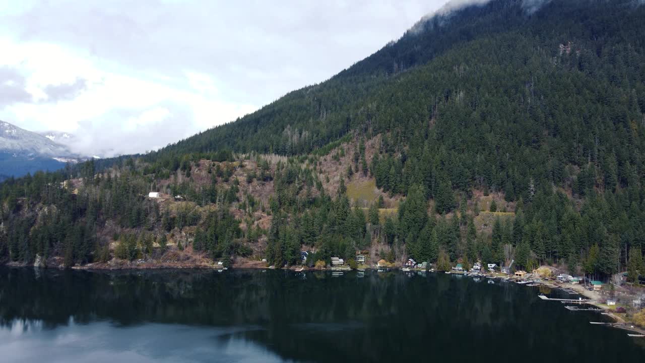 多云的山保护区:在雾蒙蒙的山峰和宁静的森林中，一个宁静的湖泊的航拍镜头视频素材