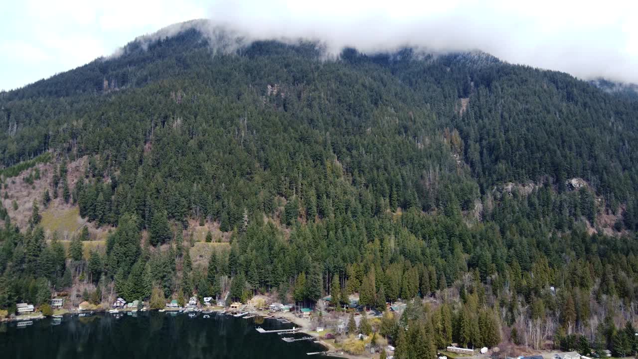 迷人的无人机视野，一个湖泊被雾蒙蒙的山峰和茂密的树冠所拥抱视频素材