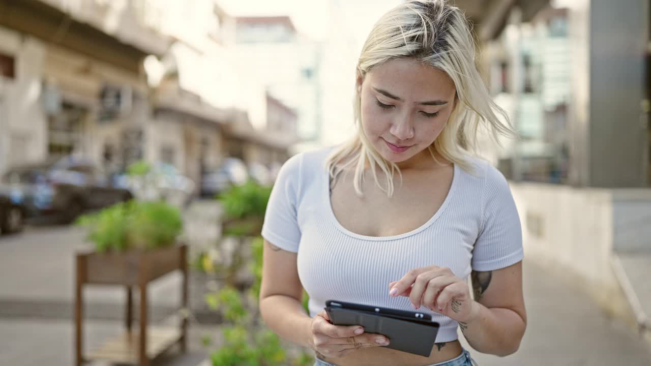 年轻美丽的西班牙女子微笑自信地使用触摸板在街上视频素材