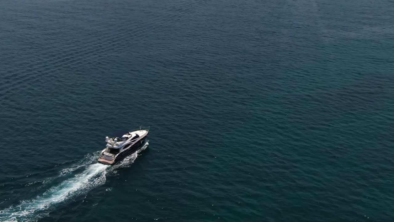 一架无人驾驶飞机飞过一艘在平静的海面上驶向城市的私人船只视频素材