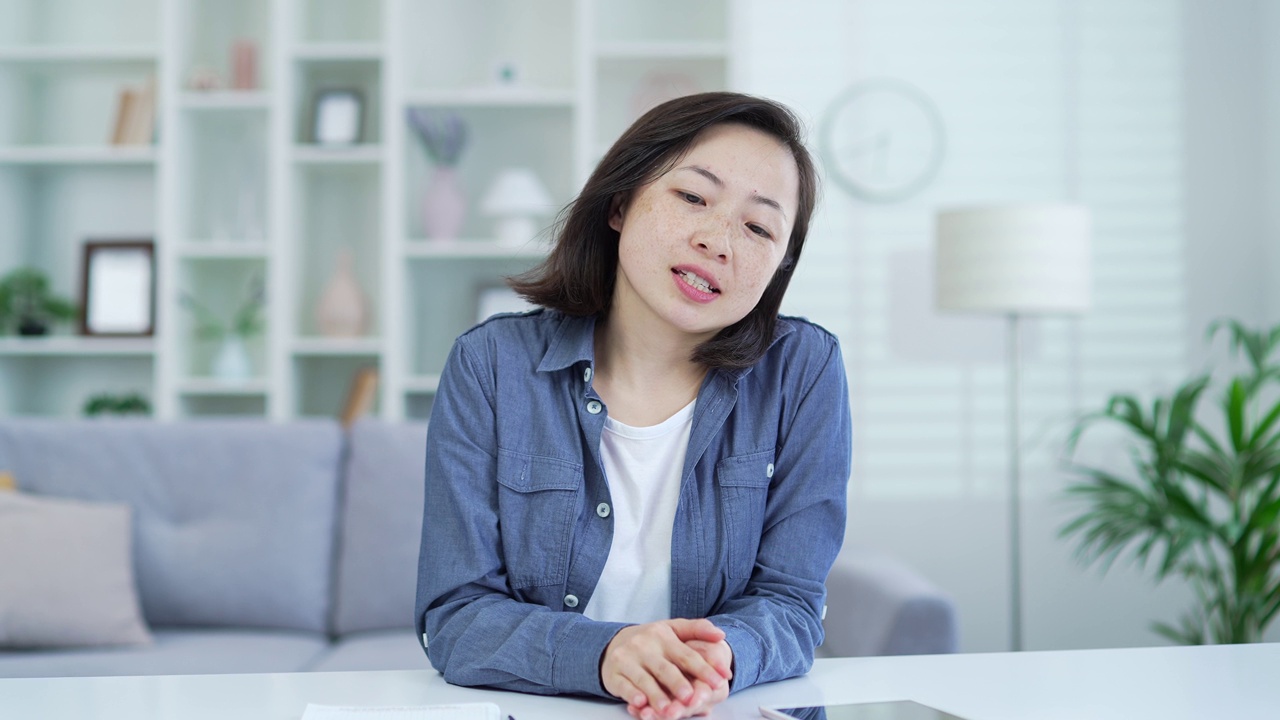 摄像头的观点。一名亚洲女性坐在办公室里看着摄像头进行视频通话视频素材