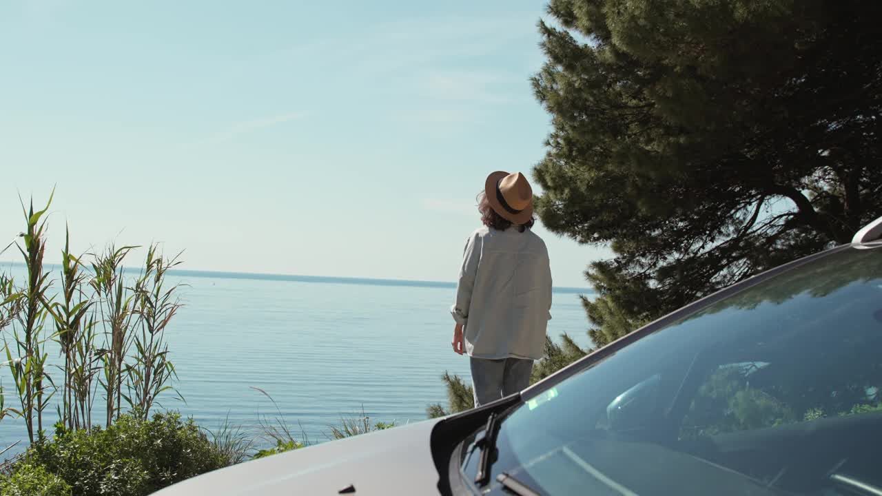 一名年轻的白人女子站在车旁边欣赏顶景视频素材