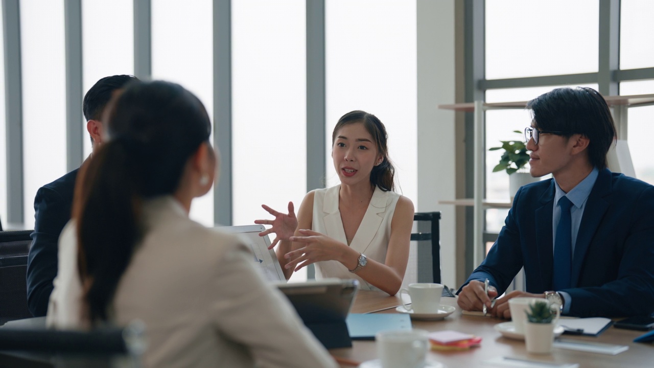 图为，一名亚洲青年女企业家在会议期间向女同事回答有关商业计划的问题。视频素材