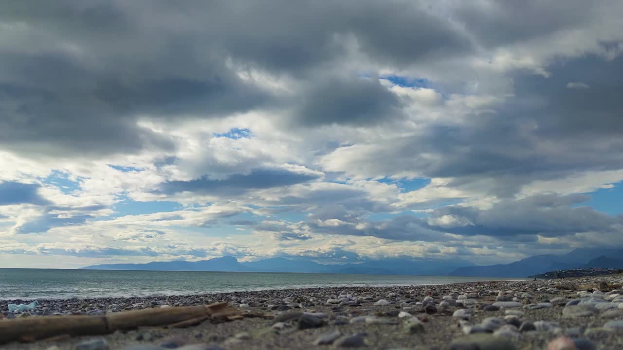 海浪冲击卵石滩。美丽的云景在海上，时间流逝视频素材