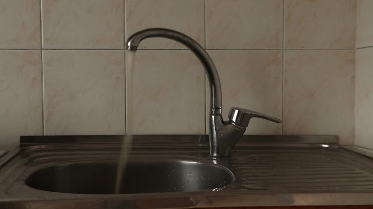 乌克兰厨房的水龙头里有生锈的水在水槽里，水质差，饮用水视频素材